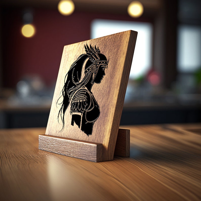 Puede incluir: Una placa de madera con una silueta negra de una mujer con casco y armadura. La placa est&aacute; sobre un caballete de madera.