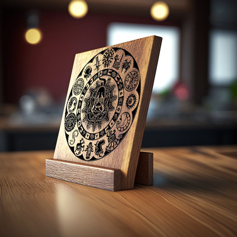 Puede incluir: Una placa de madera con un dise&ntilde;o en blanco y negro de un s&iacute;mbolo circular con una figura central y figuras que la rodean. La placa est&aacute; sobre un soporte de madera.