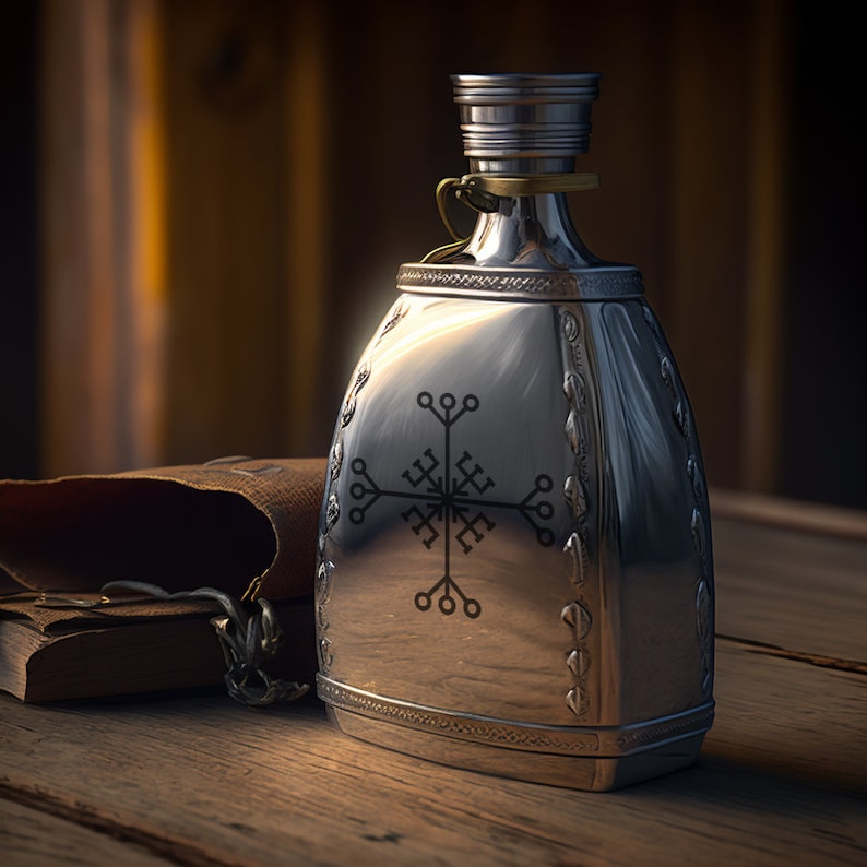 May include: A silver flask with a decorative design featuring a stylized symbol. The flask has a hinged lid and a small loop for carrying.