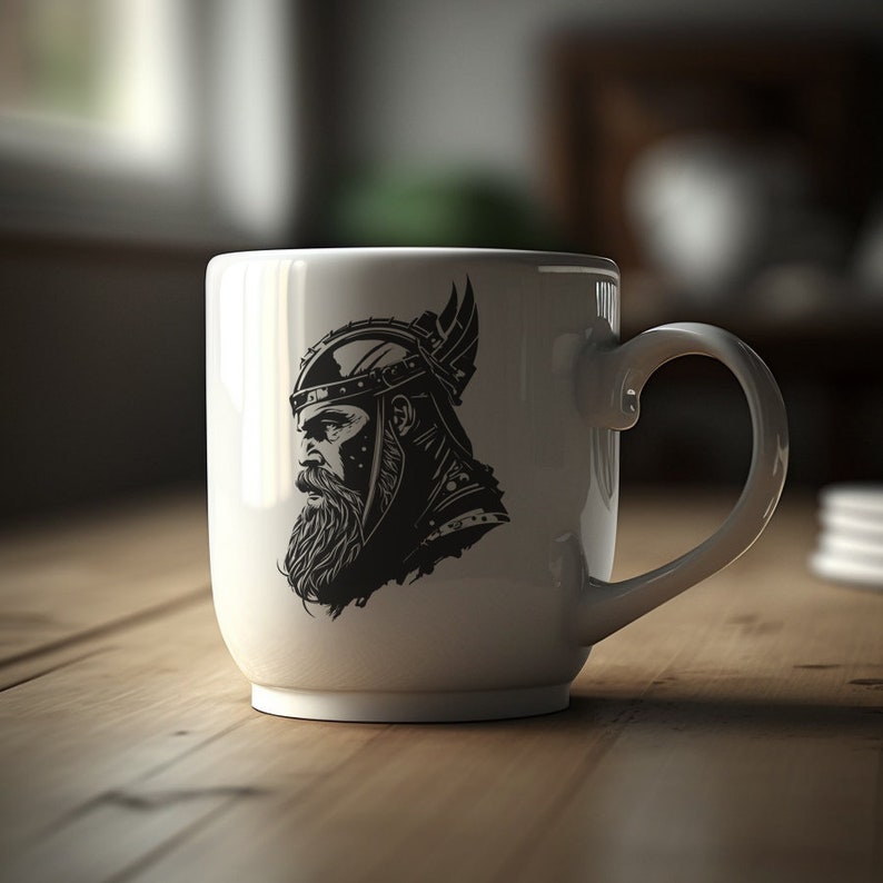May include: White ceramic mug with a black and white illustration of a Viking warrior wearing a horned helmet. The warrior is looking to the left.