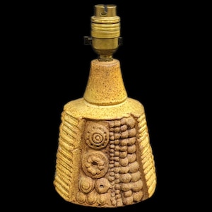 May include: A yellow ceramic table lamp with a textured base and a brass lamp socket.