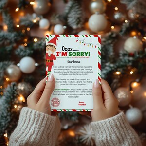 Op de afbeelding: Een rechthoekig briefje met een rood-groene zuurstokrand, een illustratie van een elf en de tekst Oops I'M SORRY! I was just catching up on some extra North Pole magic! Dear Emma, I was so tired from all the Christmas magic that I accidentally stayed in the same spot last night. Even elves need a little rest sometimes to keep our holiday sparkle shining bright! Don't worry, my magic is recharged, and tomorrow I'll be ready for a brand-new hiding place full of fun and surprises. Today's Challenge: Can you make up your silliest Christmas dance and show me? I can't wait to tell Santa all about your amazing moves at the North Pole tonight! Love, Your Elf.
