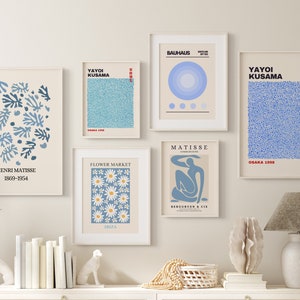 May include: A set of nine framed art prints featuring abstract designs in blue, white, and yellow. The prints are arranged in a grid pattern on a white wall. The prints feature the names of artists such as Yayoi Kusama, Henri Matisse, and Bauhaus.
