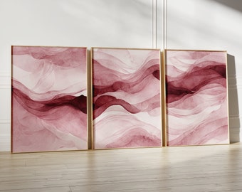 May include: Three abstract art prints in gold frames with a pink and white watercolor design. The design features flowing lines and curves.