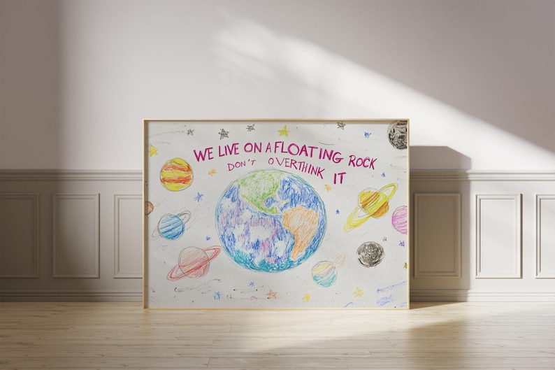 May include: A white framed print with a colorful drawing of the Earth and planets. The text reads "We live on a floating rock don't overthink it".