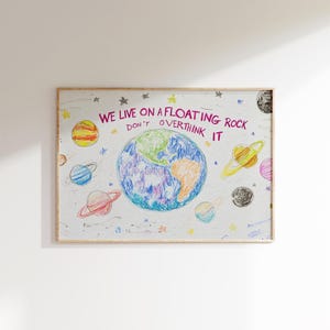 May include: A colorful drawing of the Earth with planets and stars surrounding it. The text reads "We live on a floating rock don't overthink it".
