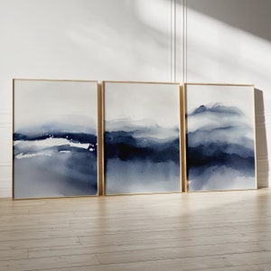 May include: Three framed abstract watercolor paintings with a blue and white color scheme. The paintings depict a landscape with a hazy, atmospheric effect.