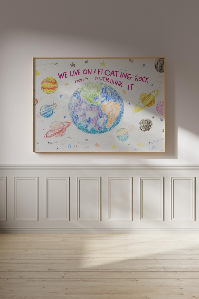 May include: A white framed poster with a colorful drawing of the Earth and planets. The text on the poster reads "We live on a floating rock. Don't overthink it."