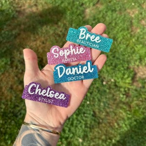 May include: Four glitter name tags with different names and job titles. The names are Bree, Sophie, Daniel, and Chelsea. The job titles are Beautician, Barista, Doctor, and Stylist.