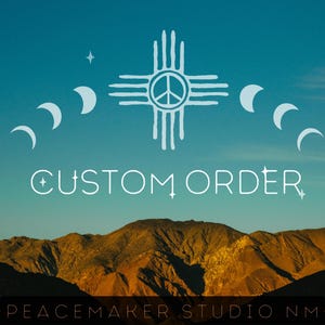 May include: A graphic design featuring a light blue Zia symbol with a peace sign center, flanked by moon phases and stars. The text CUSTOM ORDER appears below the symbol, and the text PEACEMAKER STUDIO NM is at the bottom against a mountain landscape.