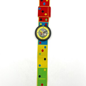 May include: A colorful wristwatch with a domino-themed band. The band features red, yellow, and green sections with polka dots. The watch face is black with a yellow border and a detailed dial.