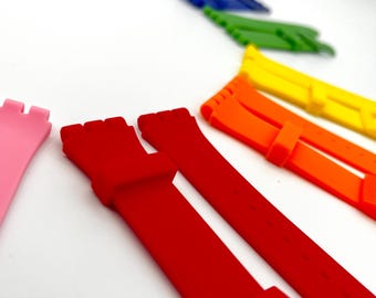 Peut inclure: Une collection de bracelets de montre colorés, dans des teintes variées, notamment rouge, orange, jaune, vert, bleu et marron. Les bracelets sont en matériau souple et sont disposés sur une surface blanche, mettant en valeur leurs couleurs vives.