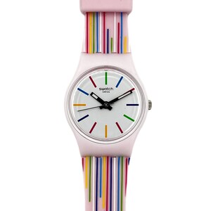Puede incluir: Un reloj Swatch rosa claro con esfera blanca y agujas negras. La correa y la parte superior del reloj están decoradas con rayas verticales de varios colores. La esfera del reloj tiene guiones de colores que marcan las horas. La palabra "swatch" y "swiss" están impresas en la esfera.