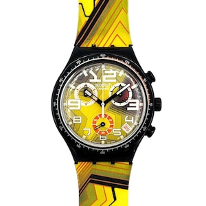 May include: A Swatch watch with a yellow and black strap and face. The watch face has a yellow background with black and white accents, and the strap features a geometric design. The watch has a black case and a date display.