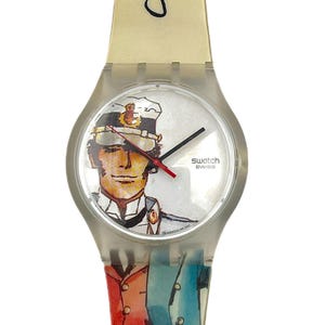 Könnte beinhalten: Swatch Swiss-Uhr mit transparentem Kunststoffarmband und Gehäuse. Das Zifferblatt zeigt eine Aquarellillustration eines Mannes in Marineuniform. Das Armband hat ein Aquarelldesign einer roten und blauen Jacke. Das Wort "Cart" ist auf dem Armband geschrieben.