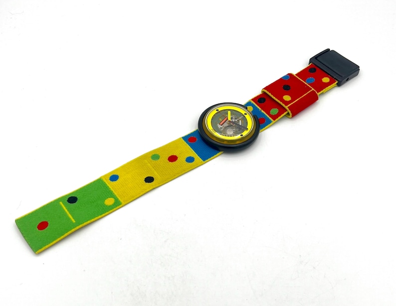 May include: A colorful wristwatch with a patterned band. The band features a yellow, green, and red design with polka dots and domino-like patterns. The watch face is round with a black bezel.