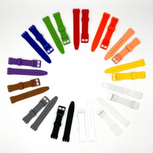 May include: A collection of 14 colorful silicone watch bands in various colors, including purple, green, red, orange, yellow, brown, gray, black, and white. The bands are arranged in a circle on a white background.
