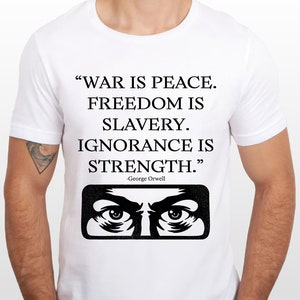 May include: White t-shirt with a black graphic print of a quote from George Orwell's novel "Nineteen Eighty-Four": "WAR IS PEACE. FREEDOM IS SLAVERY. IGNORANCE IS STRENGTH." The graphic also includes a pair of eyes.