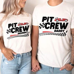 Może przedstawiać: Białe koszulki z grafiką czerwonego samochodu wyścigowego i tekstem "Pit Crew" z napisem "Mommy" i "Daddy" poniżej.