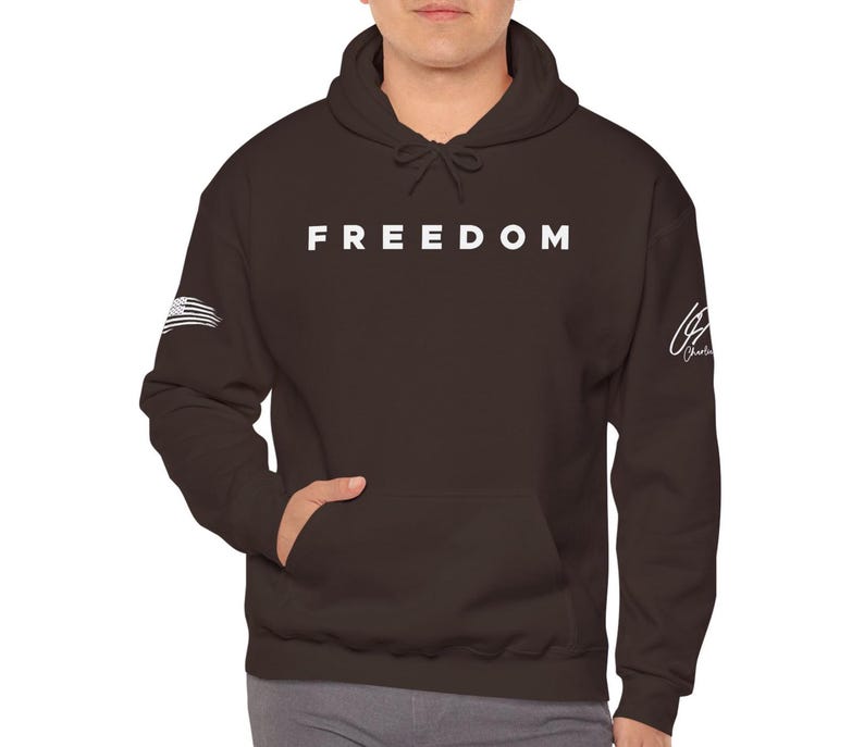 A person wearing a dark brown hooded sweatshirt with the word "FREEDOM" printed on it.