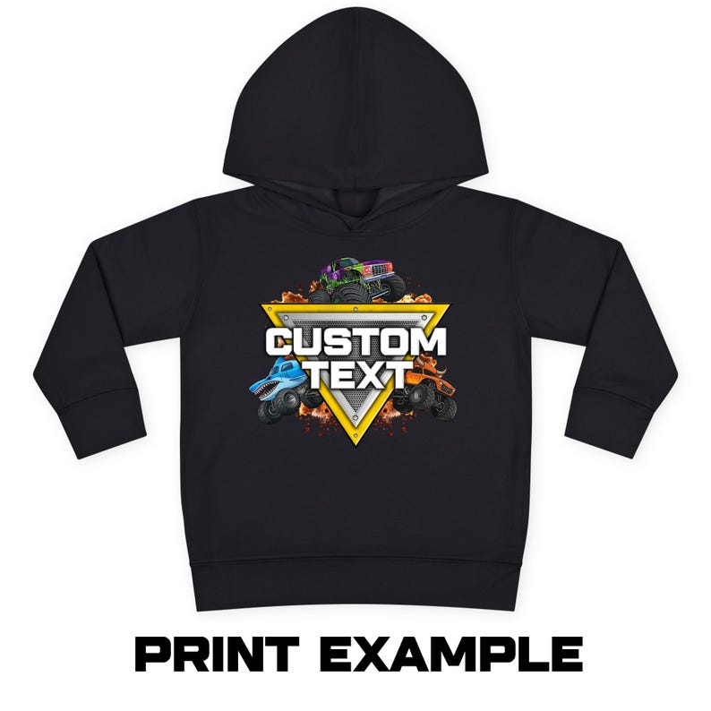 Puede incluir: Sudadera con capucha negra con un dise&ntilde;o de cami&oacute;n monstruo colorido. El dise&ntilde;o incluye un tri&aacute;ngulo amarillo con las palabras "CUSTOM TEXT" y tres camiones monstruo. El texto "PRINT EXAMPLE" est&aacute; impreso en la parte inferior.