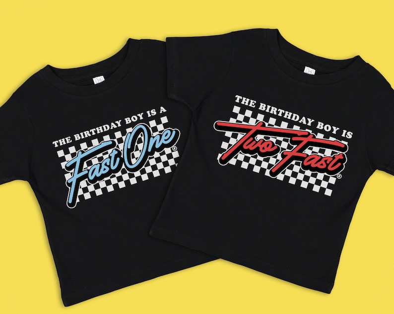 Op de afbeelding: Twee zwarte T-shirts met een geruit racevlagontwerp. Het eerste shirt zegt "The birthday boy is a Fast One" in blauwe tekst. Het tweede shirt zegt "The birthday boy is Two Fast" in rode tekst.