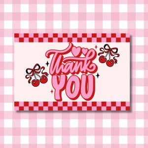 May include: A rectangular card with a light pink background and a red and pink checkered border. The words "Thank You" are in a retro font, with two cherries and bows on either side.