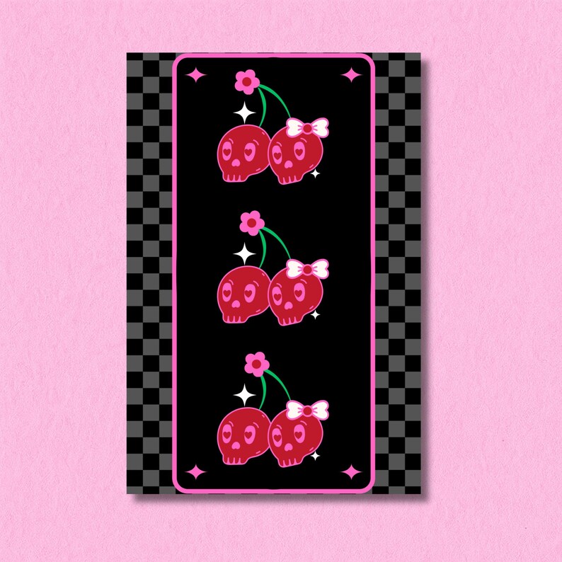 May include: A vertical print featuring three sets of red skull cherries with pink bows and green stems on a black background. The print is framed by a pink border with star accents and a black and gray checkered pattern.