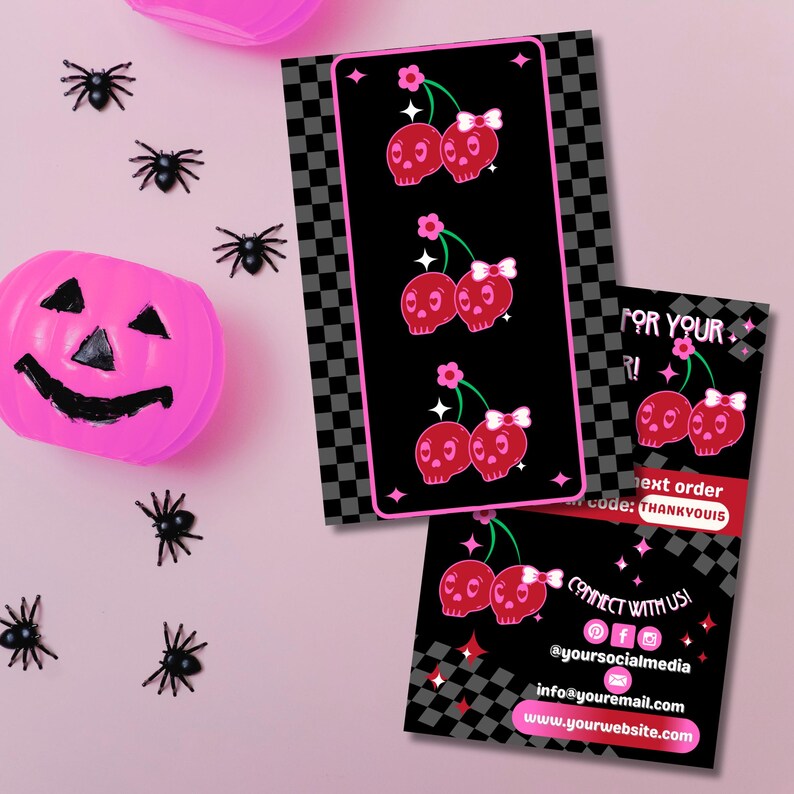 May include: A pink Halloween-themed image with a pink pumpkin, plastic spiders, and business cards. The cards feature a black background with a checkerboard pattern and cherry skull graphics. The cards also include the text "FOR YOUR R!" and "CONNECT WITH US!"