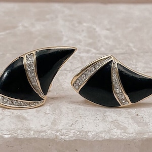 Könnte beinhalten: Ein Paar schwarze und goldene Ohrringe mit geometrischem Design. Die Ohrringe sind mit kleinen, klaren Strasssteinen verziert.