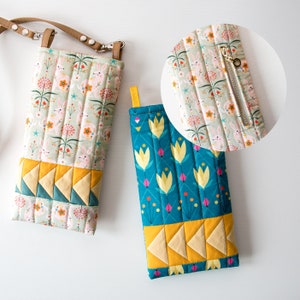 May include: Two quilted fabric phone cases with zipper closures. One case features a green and white floral pattern with bunnies. The other case features a blue and yellow floral pattern with tulips.