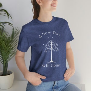 May include: A navy blue t-shirt with a white graphic of a tree with the text "A New Day Will Come" printed on it.