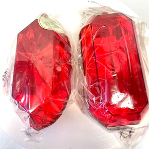 May include: Two red, faceted, plastic, gem-shaped ornaments wrapped in clear plastic.