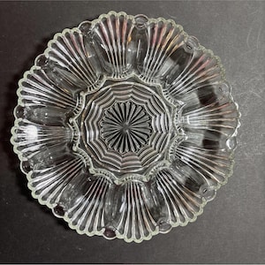 Könnte beinhalten: Klarer Servierteller aus Glas mit gewelltem Rand und einem Sternmuster in der Mitte. Der Teller ist in Abschnitte unterteilt, ideal zum Servieren von Vorspeisen oder Snacks. Das Glas ist transparent.