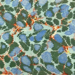 May include: A decorative paper with a marbled pattern. The design features blue, green, and red swirls and shapes on a light blue background. The pattern is reminiscent of feathers or floral elements.