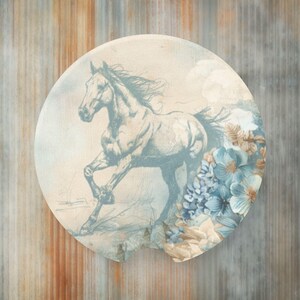 May include: A vintage-style illustration of a white horse running through a field of blue and brown flowers. The image is on a round, cream-colored background.