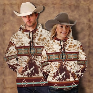 May include: A pair of brown and white cowhide print hoodies with a geometric pattern in shades of red, blue, and turquoise. The hoodies have a drawstring hood and a kangaroo pocket.