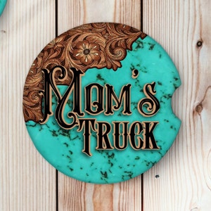 May include: A round turquoise and brown coaster with a tooled leather design and the text "MOM'S TRUCK" in black and gold lettering.