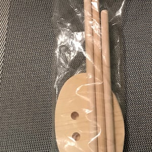 May include: A set of wooden craft supplies for making a wooden sign. The set includes a wooden oval shape with two holes and three wooden dowels.
