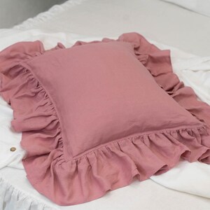 Puede incluir: Una almohada rosa polvorienta con un borde de volantes. La almohada est&aacute; hecha de una tela de lino suave y es perfecta para agregar un toque de elegancia a cualquier habitaci&oacute;n.