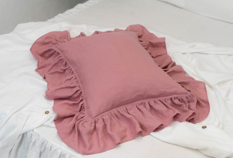 Puede incluir: Una almohada rosa polvorienta con un borde de volantes. La almohada est&aacute; hecha de una tela de lino suave y es perfecta para agregar un toque de elegancia a cualquier habitaci&oacute;n.