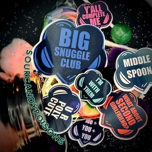 May include: A collection of colorful stickers with various phrases, including "Big Snuggle Club", "Y'all Complete Me", "Middle Spoon", "I'm With Them", "What About Second Girlfriend?", "U Pour Cutie", and "Me + You + You".