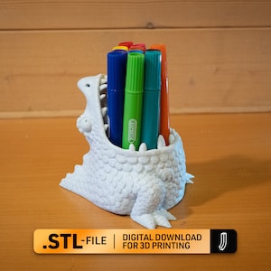 Könnte beinhalten: Weißer, 3D-gedruckter Stifthalter in Dinosaurierform mit einem weit geöffneten Maul, der eine Vielzahl von bunten Markern hält.  .STL-FILE | DIGITALER DOWNLOAD ZUM 3D-DRUCK