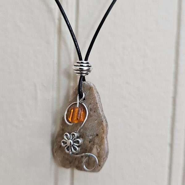 Small river rock necklace with tiny flower and orange bead. 10 in length