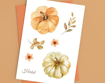 Puede incluir: Ilustración en acuarela de calabazas, hojas y flores sobre una tarjeta blanca. Las calabazas son naranjas y verdes, con tallos marrones. La palabra "Herbst" está escrita en cursiva. La tarjeta está dentro de un sobre naranja.