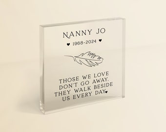 Può includere: Un blocco di vetro trasparente con un design a forma di piuma nera e il testo "NANNY JO 1968-2024" e "QUELLI CHE AMIAMO NON VANNO VIA, CAMMINANO AL NOSTRO FIANCO OGNI GIORNO."