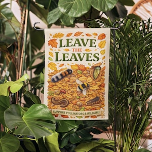 Może przedstawiać: Flaga ogrodowa z napisem "LEAVE THE LEAVES" i ilustracją jesiennych liści, owadów i pszczoły. Flaga zawiera również napis "SUPPORT POLLINATORS & WILDLIFE!"