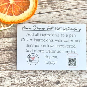May include: White card with instructions for a mini simmer pot kit. The instructions read: "Add all ingredients to a pan. Cover ingredients with water and simmer on low. Uncovered. Add more water as needed. Repeat. Enjoy!" A small pink heart with a house inside is in the bottom left corner. A QR code is in the bottom right corner with the text "Scan me" above it.