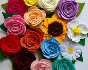 May include: A collection of colorful felt flowers, including roses, a sunflower, and daisies, arranged in a circular pattern. The flowers are in shades of pink, yellow, orange, blue, purple, white, and green. Each flower has a green felt leaf base.