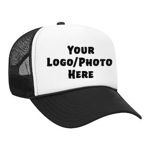 May include: A black and white trucker hat with a white front panel. The front panel features the text "YOUR LOGO/PHOTO HERE" in bold, black letters. The hat has a black brim and a black mesh back.